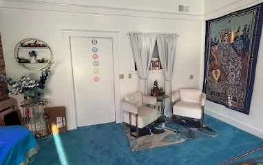 Private Petaluma reading room with two cream armchairs, a chakra-symbol door and a tarot tapestry